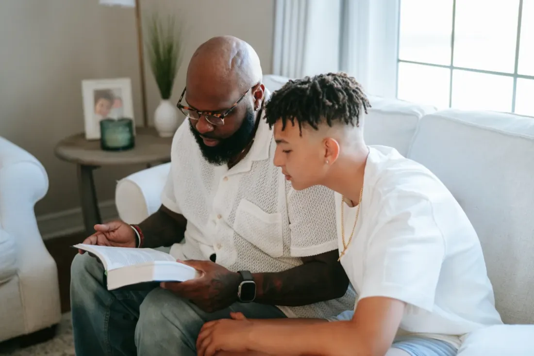 A father and his teenage son reading together